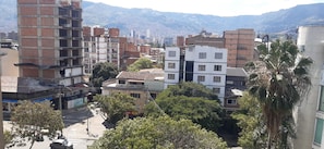 A multi-story building with a mix of residential and commercial spaces, surrounded by trees and a mountainous backdrop. - Cold AC fast Wi-Fi great location  (Medellín)