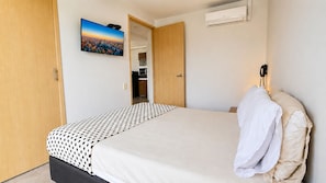 A bedroom with a bed, a wardrobe, a television, and an air conditioning unit. - Cold AC fast Wi-Fi great location  (Medellín)