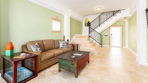 A spacious living room with a brown sofa, a coffee table, and a staircase leading to another level.