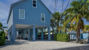 A two-story blue house with a covered porch and a gravel driveway.