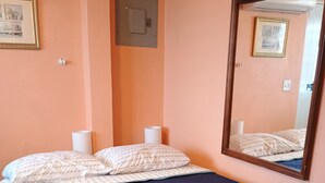 A bedroom with a bed, two bedside lamps, a wall-mounted air conditioner, and a framed picture on the wall. - BioBay Inn Apt C - Cute Tiny Studio w/wifi & AC Near Malecon, Sun Bay (Vieques)