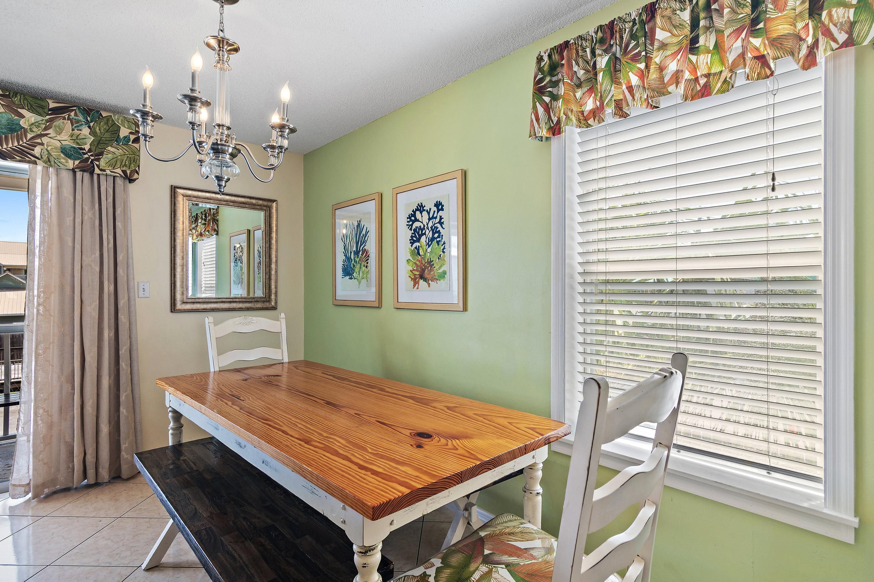 A dining area with a wooden table, chairs, a chandelier, and framed artwork on the wall.