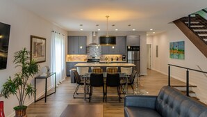 Une cuisine moderne dotée d’un îlot central, d’un coin repas avec des chaises et d’un escalier.