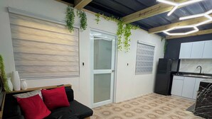 A compact living space with a sofa, a sliding door, a kitchen area, and patterned flooring.