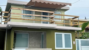 A two-story house with a balcony, a garage, and a gated entrance.