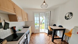 A compact kitchen with wooden cabinets, a black stove, and a hexagonal patterned floor. - Les Chouans - Holiday home (Les Sables-d´Olonne)