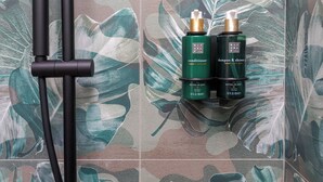 Un baño con cabezal de ducha y dos botellas de acondicionador y champú Ritual of Jing.
