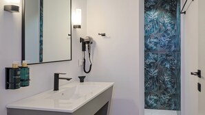 Un baño moderno con un espejo grande, un lavabo blanco y un secador de pelo fijado en la pared.