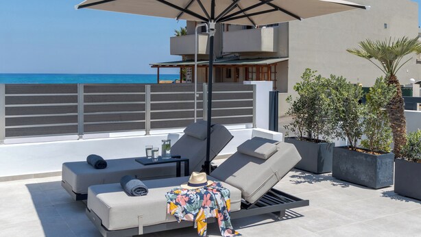 Un espacio moderno al aire libre con mesa de billar, sillones de descanso y una sombrilla grande.