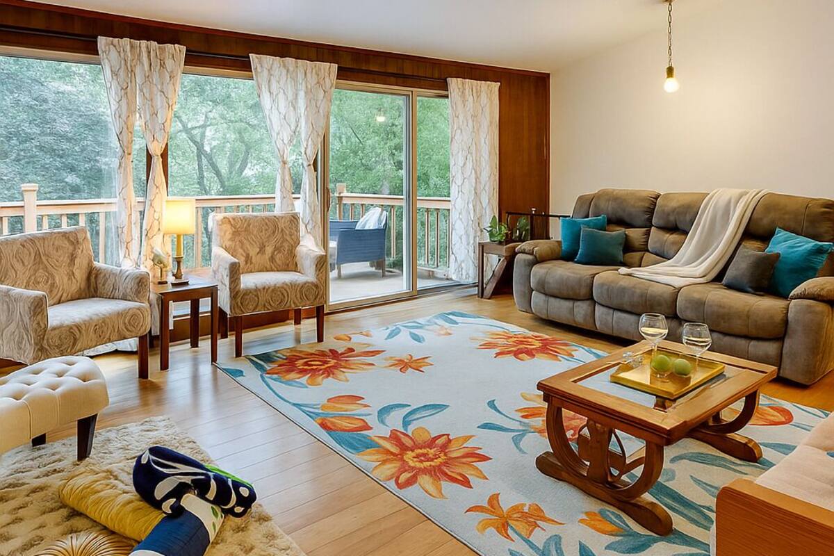 A spacious living room with a sofa, chairs, a coffee table, and a view of a balcony.