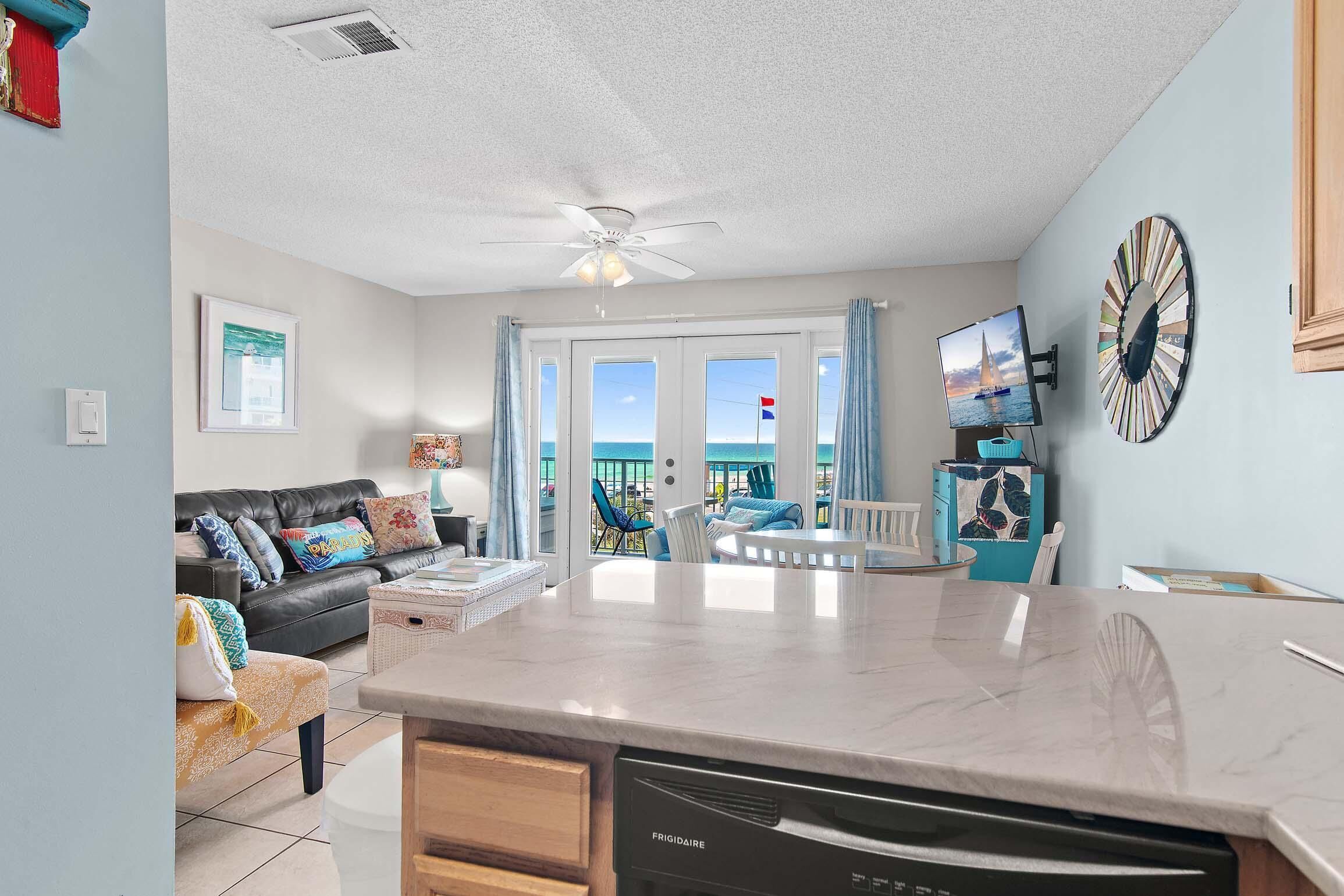 A spacious living area with a kitchen island, a dining table, and a view of the sea through large windows.