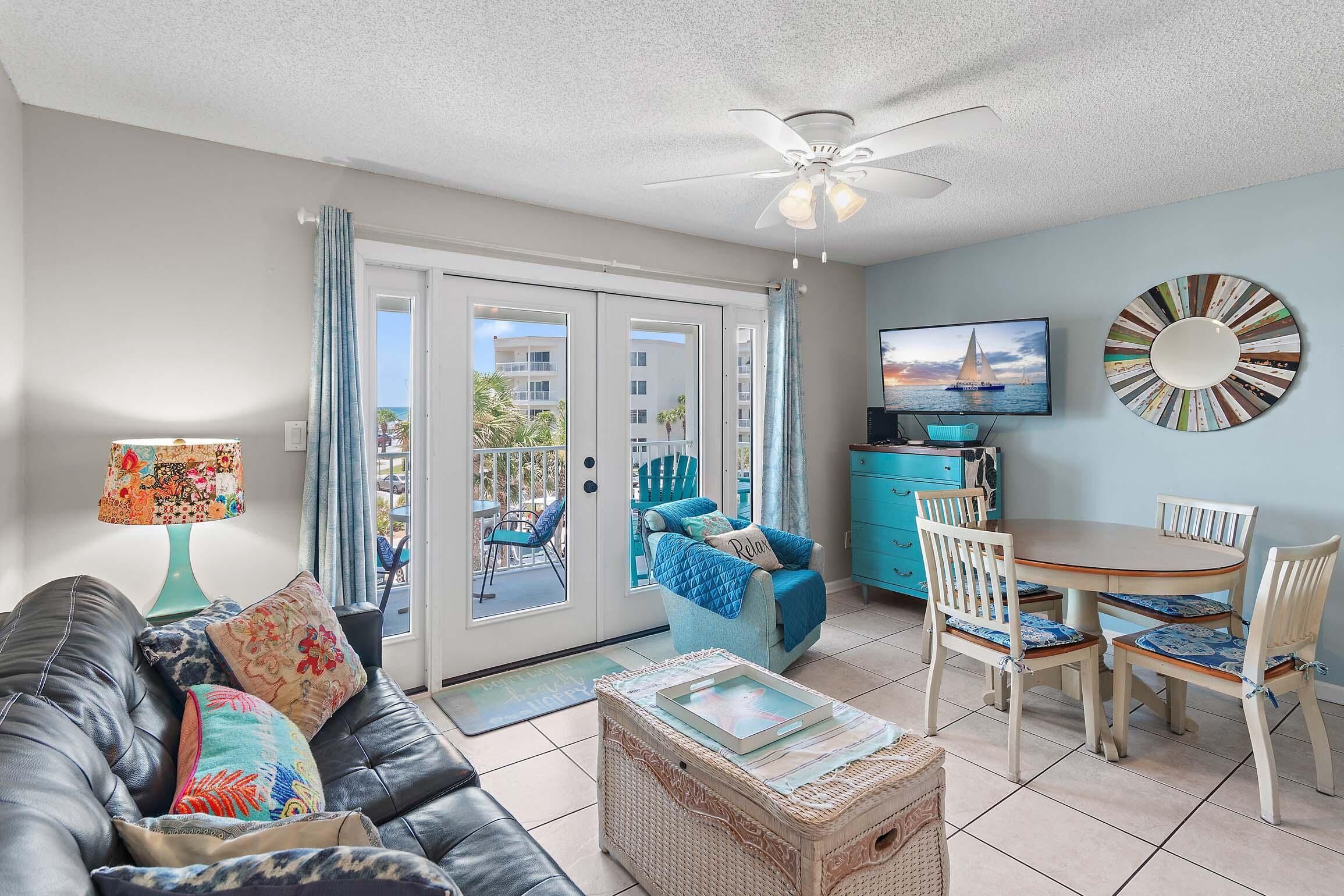 A living room with a sofa, a coffee table, a TV, and a dining area with chairs and a table.