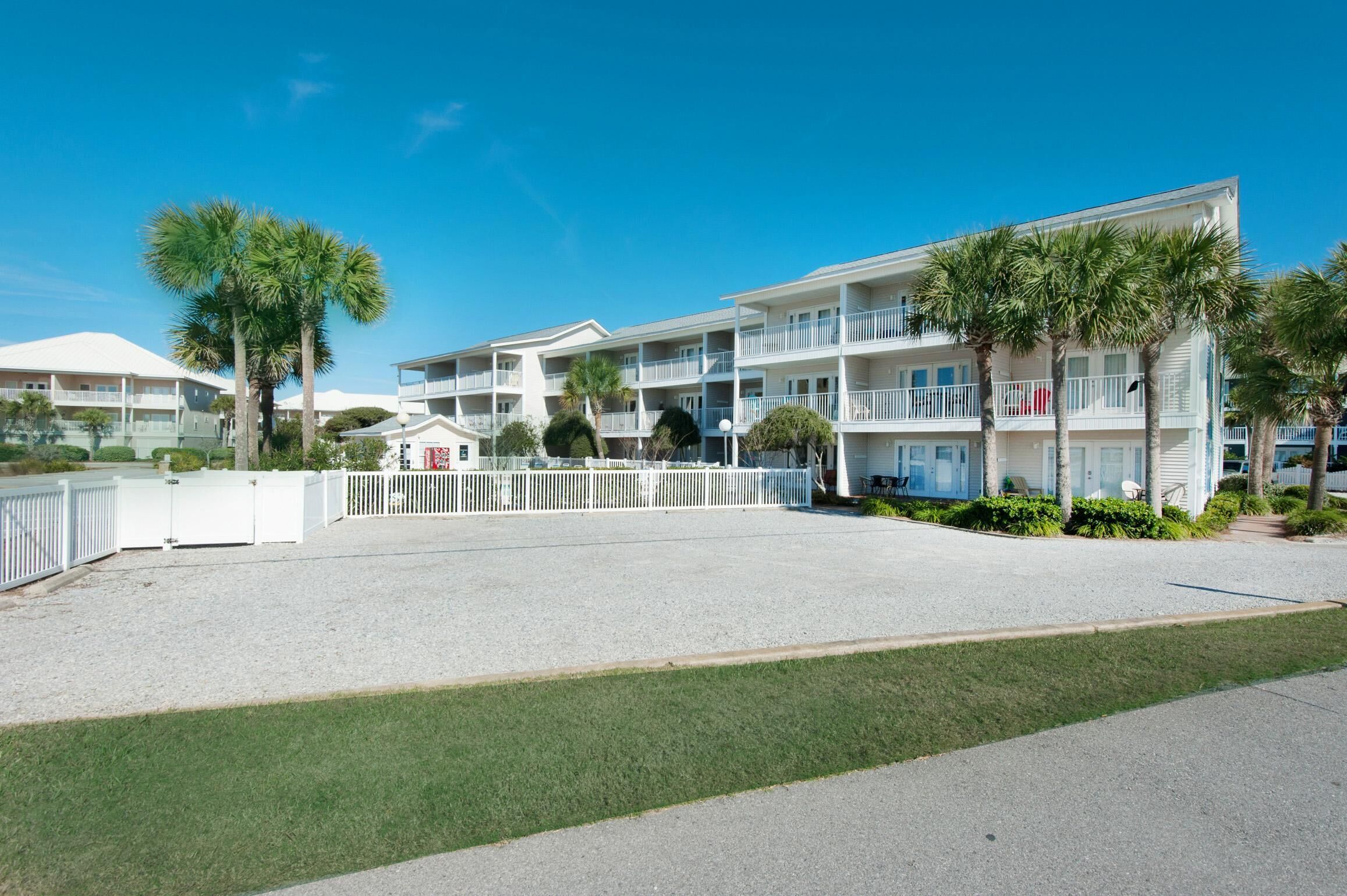 A beachfront hotel with multiple balconies, palm trees, and a clear blue sky.