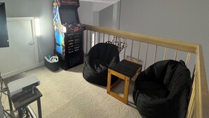 A room with a ceiling fan, a small table, a bean bag chair, and a gaming console.