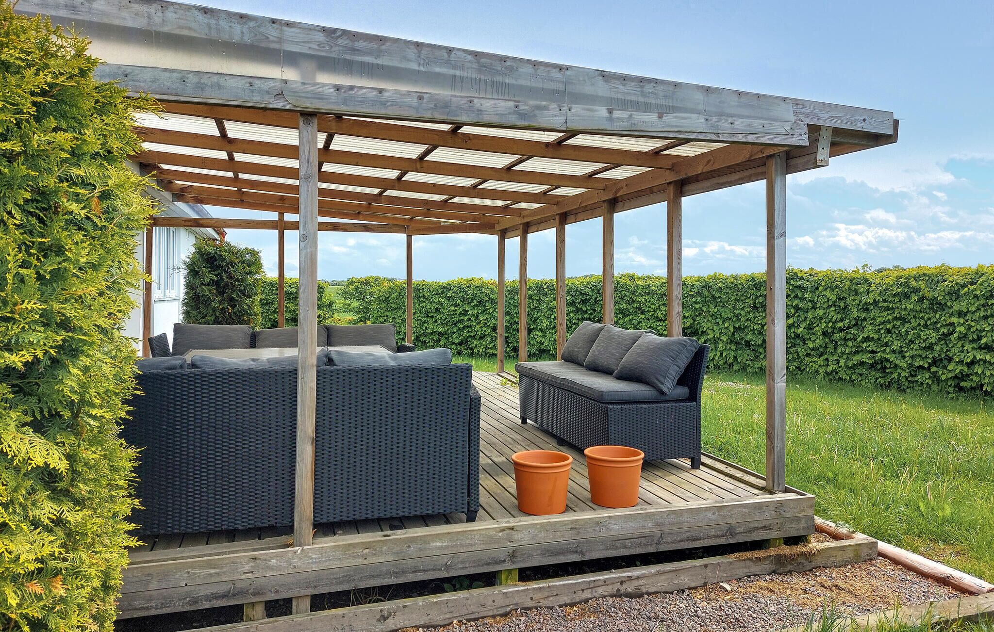 An outdoor patio with wicker furniture and a pergola.