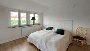 A bedroom with a bed, a chair, a window with a view, and a radiator. - 2 bedroom beautiful home in Fleninge (Fleninge)