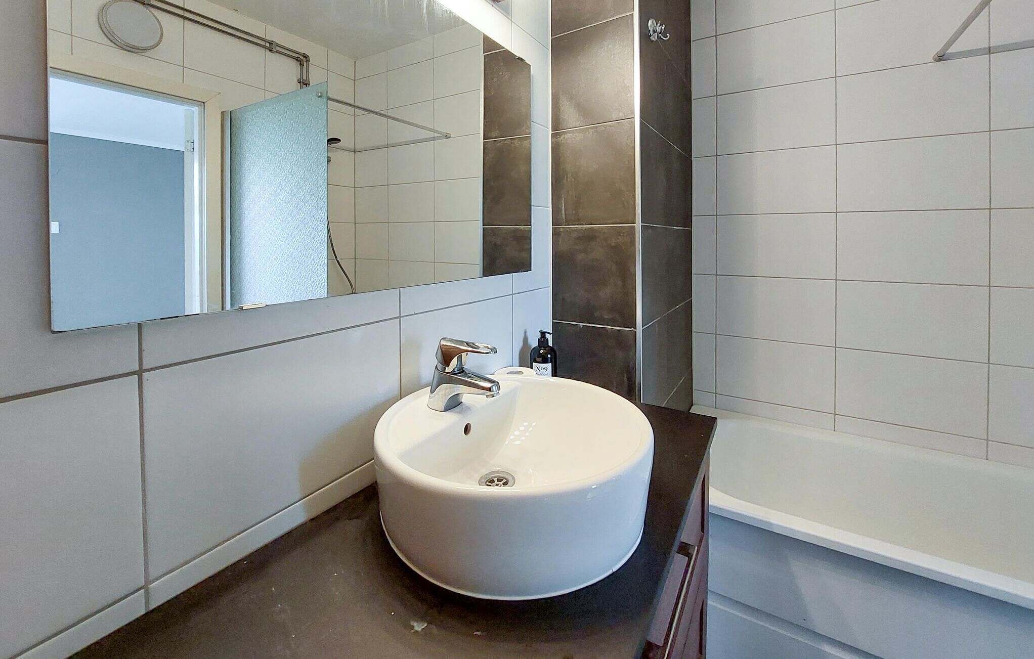 A modern bathroom with a white sink, a mirror, and a shower.