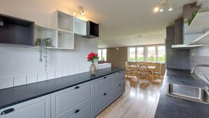 A modern kitchen with white cabinetry, a black countertop, and a dining area with wooden chairs. - 2 bedroom beautiful home in Fleninge (Fleninge)