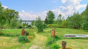 A garden pathway leading to a body of water, surrounded by trees and greenery. - Gorgeous home in Ryd with sauna (Ryd)