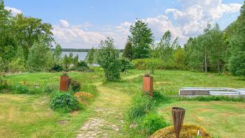 Un sentier de jardin qui mène à un plan d’eau, entouré d’arbres et de verdure.