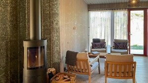 A cozy living room with a wood-burning stove, two chairs, a table, and a box of firewood. - 2 bedroom cozy home in Lärbro (Lärbro)