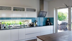 A modern kitchen with white cabinets, a black countertop, and a view of greenery outside.