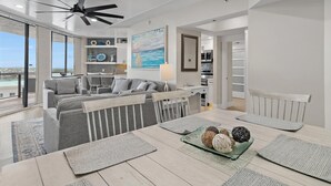 A modern living room with a grey sofa, dining table, and a ceiling fan. - Surfside Resort #1406 (Miramar Beach)