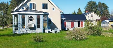 A two-story house with a covered porch and a red barn in the background.