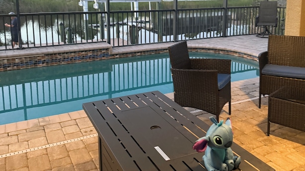 An outdoor pool area with a view of a lake and houses in the background.