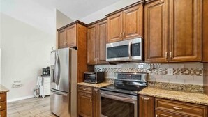 A kitchen with wooden cabinets, stainless steel appliances, and a tiled backsplash.
