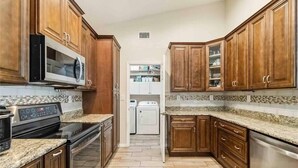 A kitchen with wooden cabinets, a microwave, an oven, and a dishwasher.