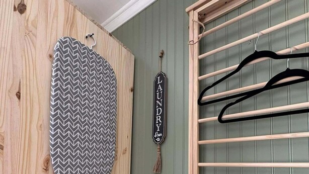 A laundry room with a wooden wall, a hanging rack, and two containers labeled for laundry supplies. - The Clover Cottage - Rolla's St.Pat's Themed house near S&T, Acorn Trail & more! (Rolla)
