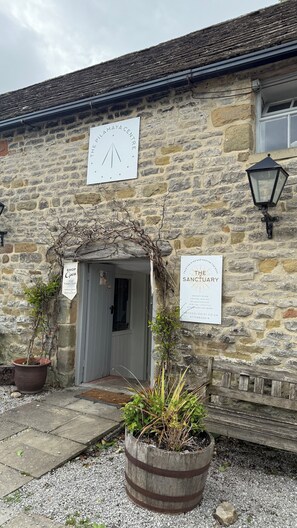 A stone building with a sign for 'The Pilamaya Centre' and another for 'The Sanctuary' offering services like therapy and crystal healing. - Eyam hikers hideaway. (Eyam)