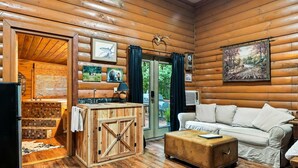 Ein Holzblockhaus-Innenraum mit einer hölzernen Bank, einem weißen Sofa, einer Holzschrank und einem Gemälde an der Wand.