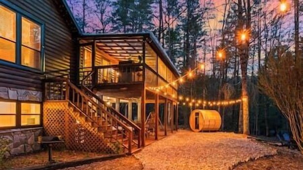 Eine Holzhütte mit überdachter Veranda, einer Treppe und Lichterketten.