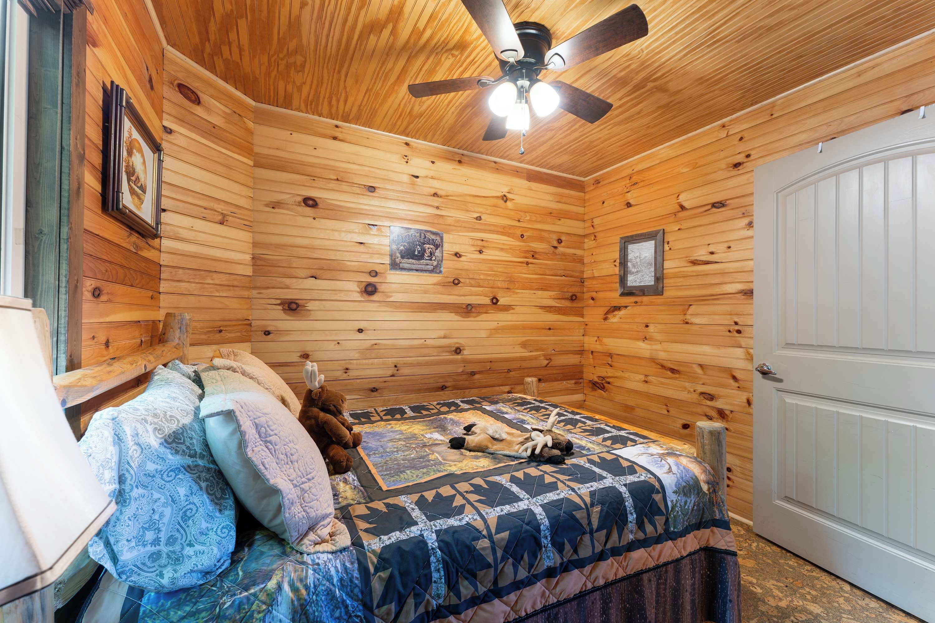 Dormitorio de cabaña de madera con una cama, un ventilador de techo y una puerta.