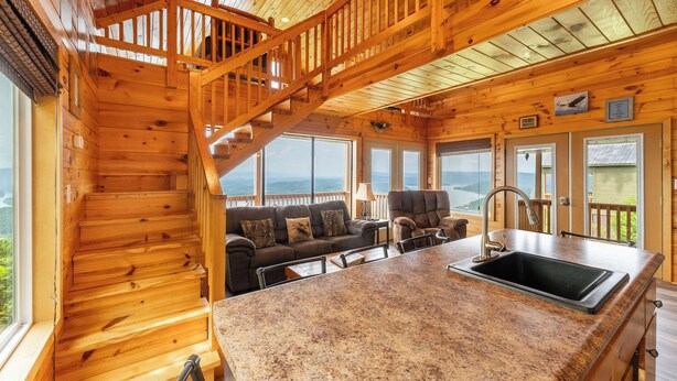 L’intérieur d’une cabane en bois comprend un espace cuisine, un escalier et une vue sur l’extérieur.