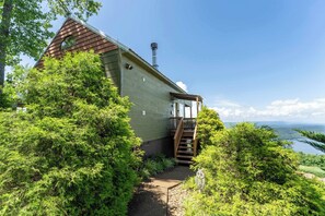 Une maison avec une façade en bois, une cheminée et un escalier menant à une terrasse.