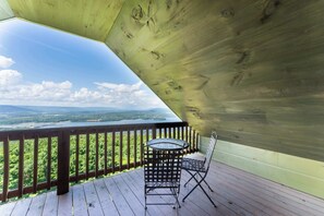Une terrasse en bois avec une table et des chaises, offrant une vue sur un paysage magnifique.