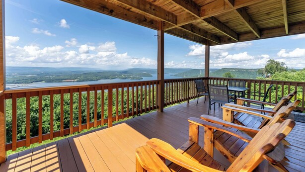 Una terraza de madera con vistas a un lago y montañas.