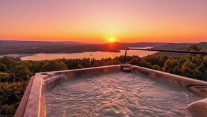 Un bain à remous avec vue sur un coucher de soleil se reflétant sur un lac et des collines.