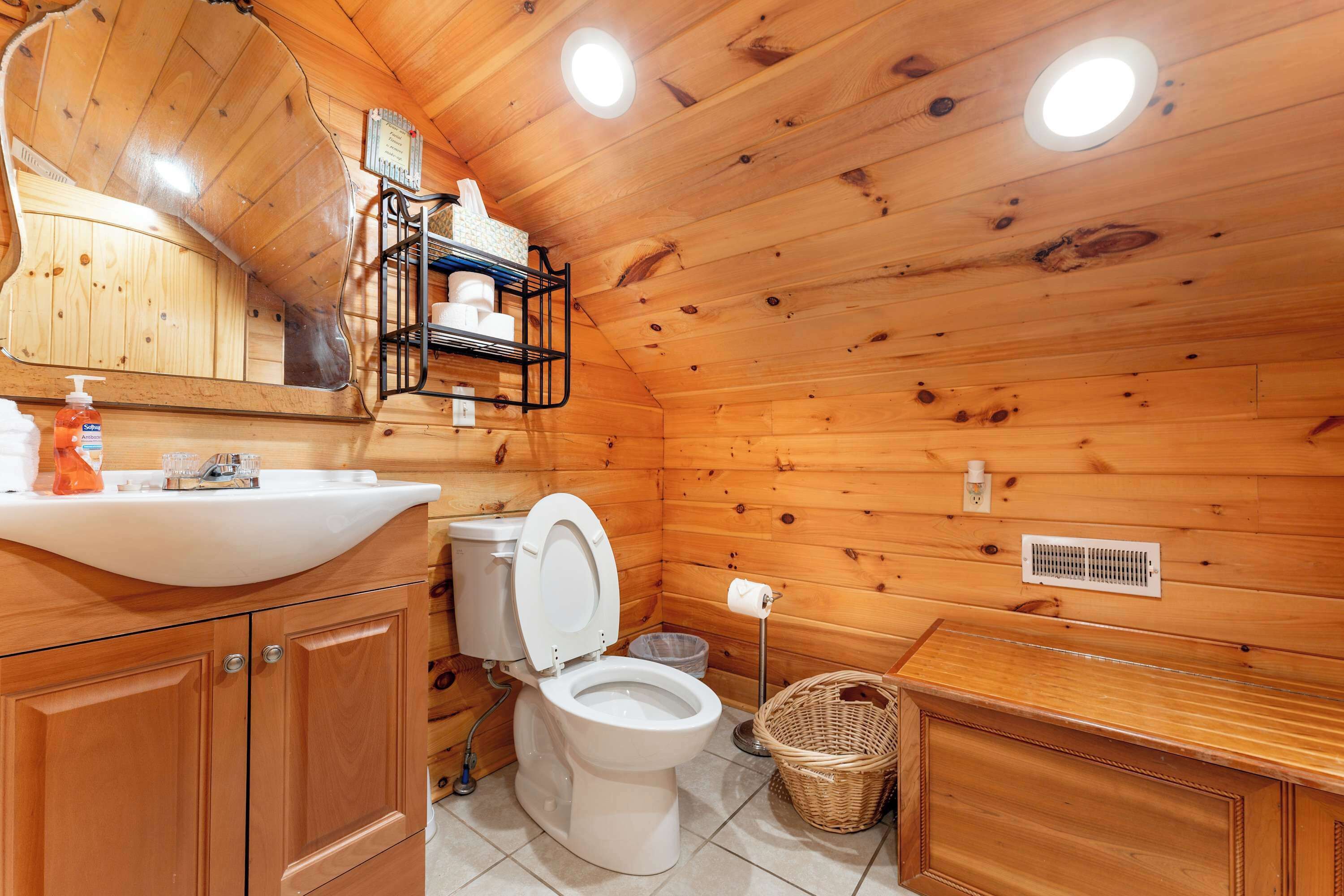 Ein Badezimmer einer Holzhütte mit Toilette, Waschbecken und Spiegel.