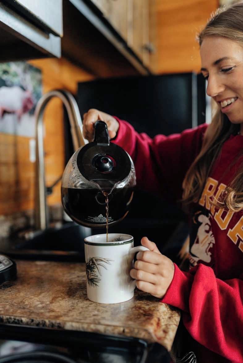 A person pouring liquid from a kettle into a mug on a kitchen counter.