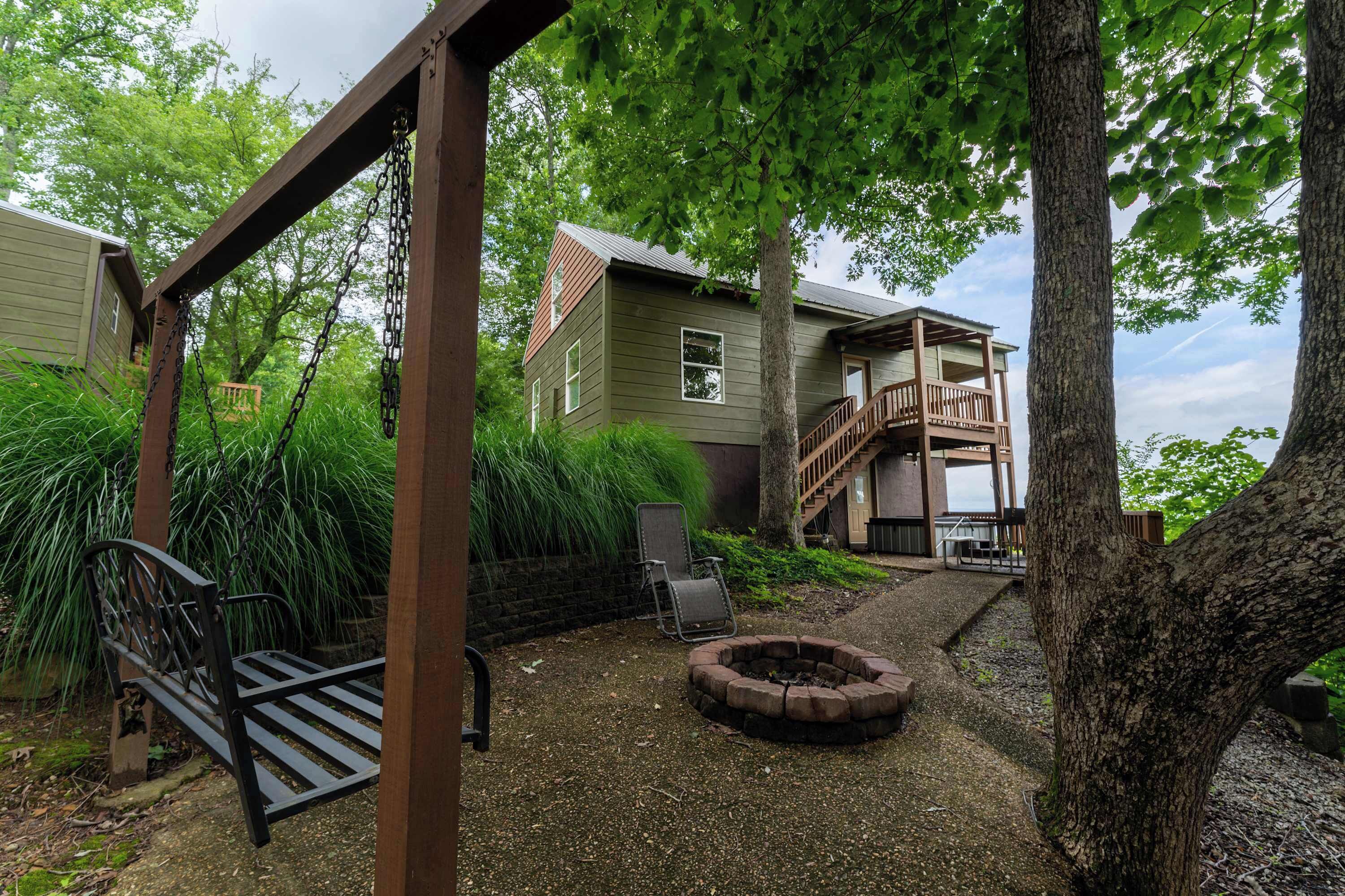 Une terrasse en bois avec une balançoire, un foyer et un banc.