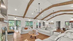 A spacious living room with white sofas, a wooden coffee table, and a fireplace. - Hummingbird Cabin with a private hot tub! (Bryant)