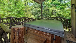 A hot tub on a wooden deck with a view of a forest. - The Cabins at Seven Foxes (Lake Toxaway)