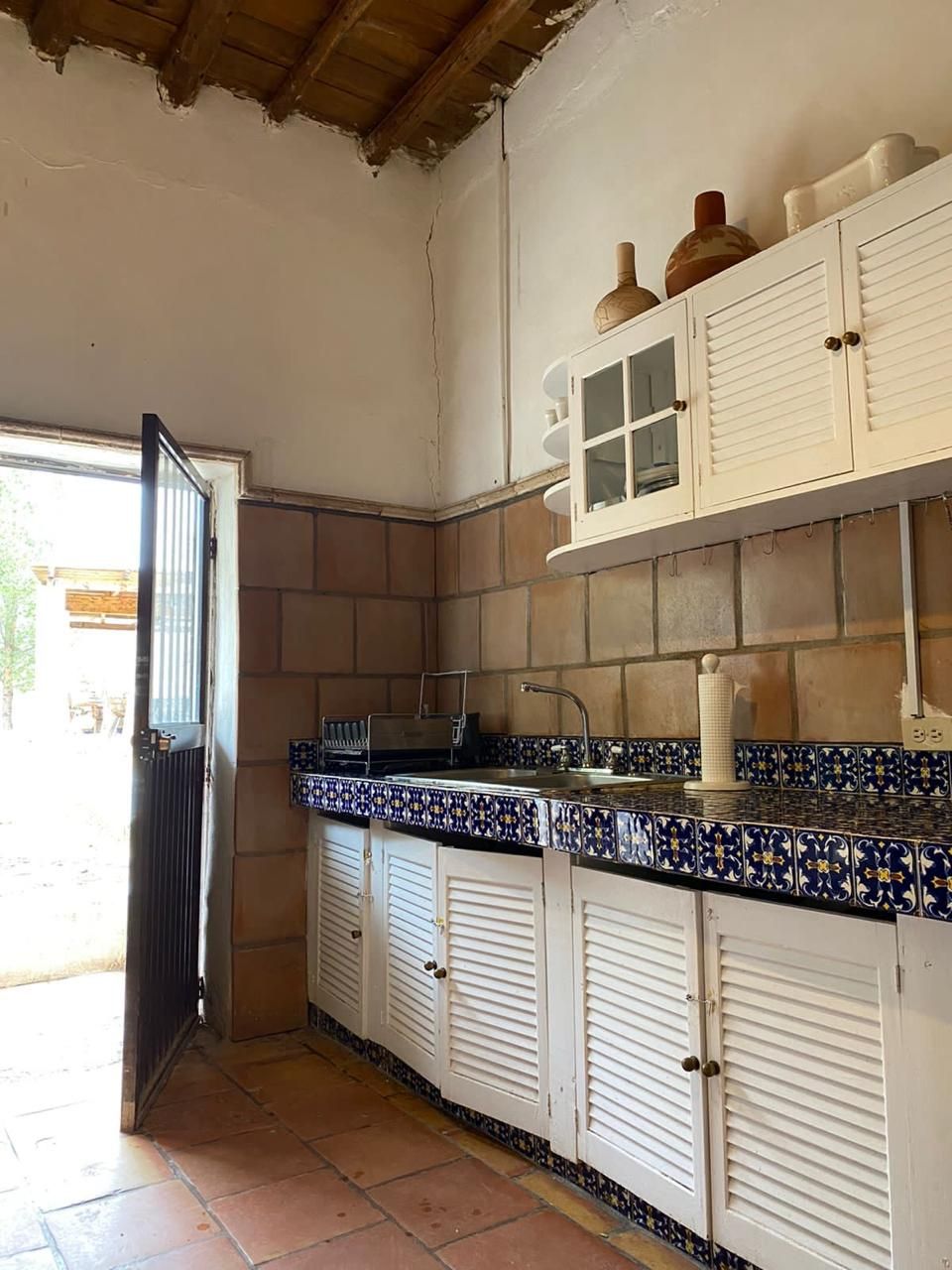 A kitchen with white cabinets, a tiled backsplash, and a black countertop.
