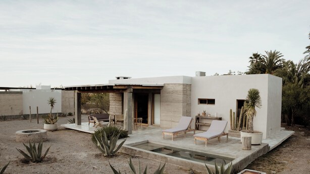 Un patio moderno al aire libre con sillones de descanso, una piscina pequeña y plantas de desierto.
