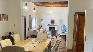 Un comedor con una mesa y sillas de madera, una chimenea y un candelabro.