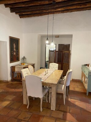 A dining area with a wooden table, white chairs, and hanging pendant lights. - Las Pudencianas Hotel Vitivinícola (Parras de la Fuente)